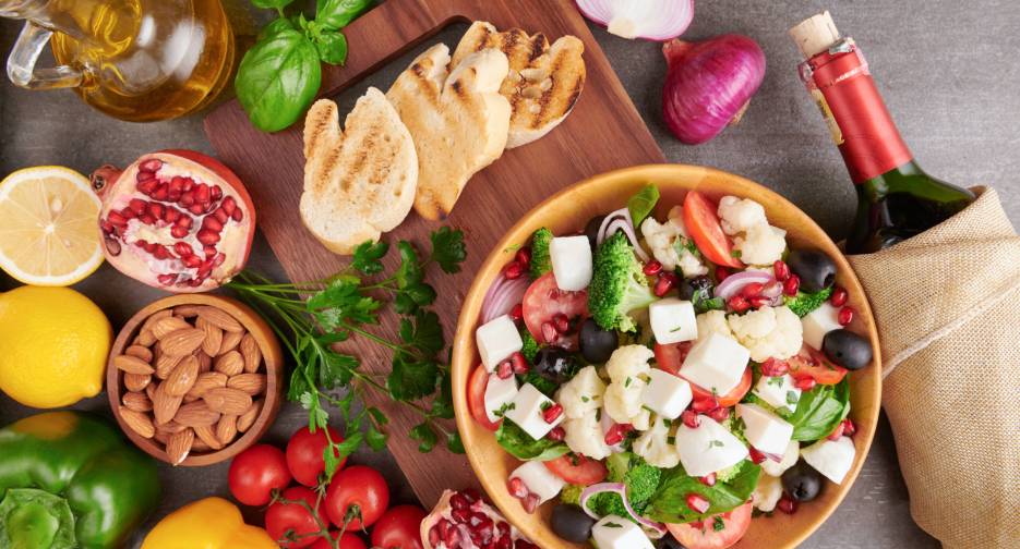Greek salad or horiatiki with large pieces of tomatoes, cucumbers, onion, feta cheese and olives in white bowl isolated top view. Village salad with diced mozzarella, arugula, parsley and olive oil